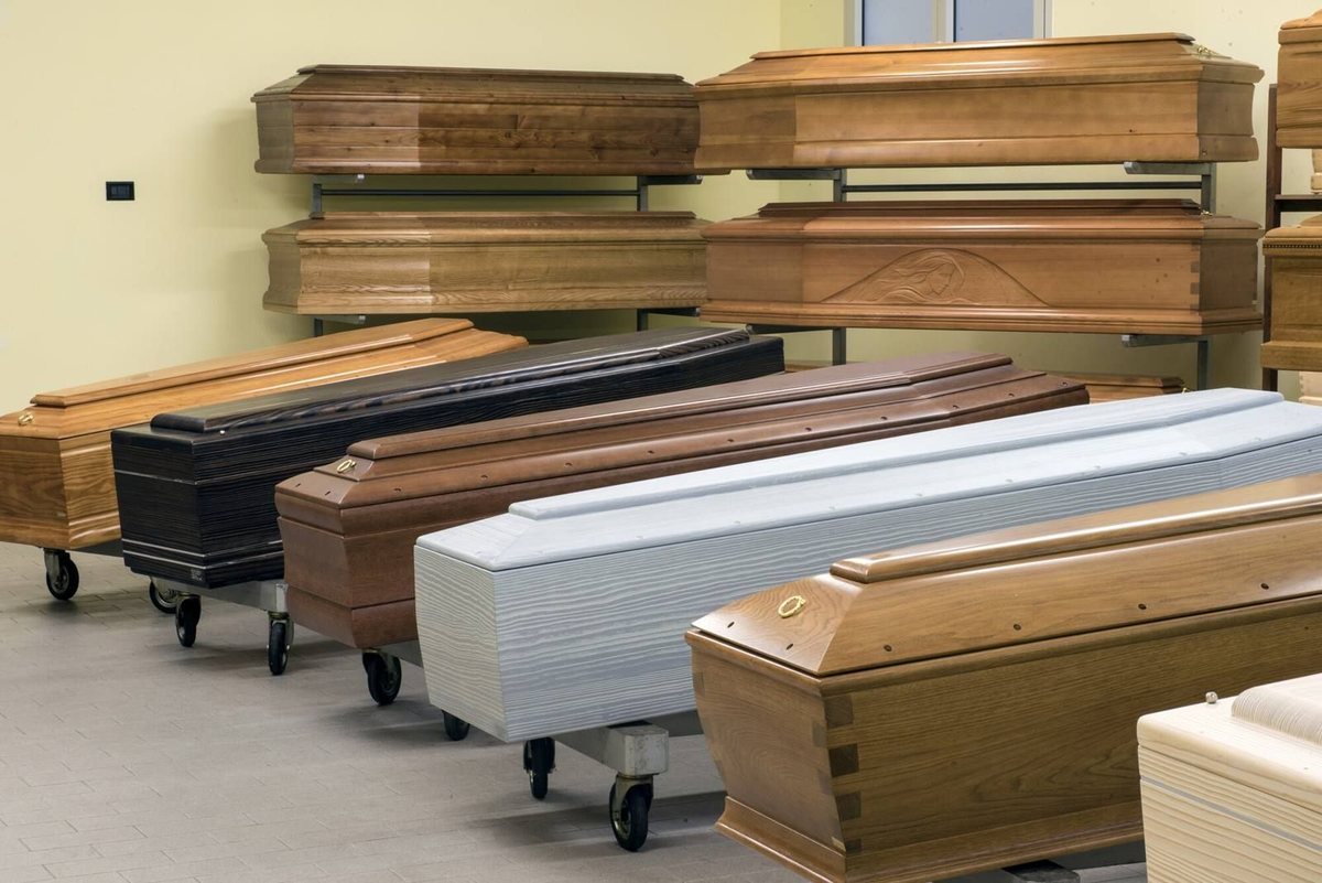 Esposizione di cofani in legno di diverse essenze e uno bianco su carrelli